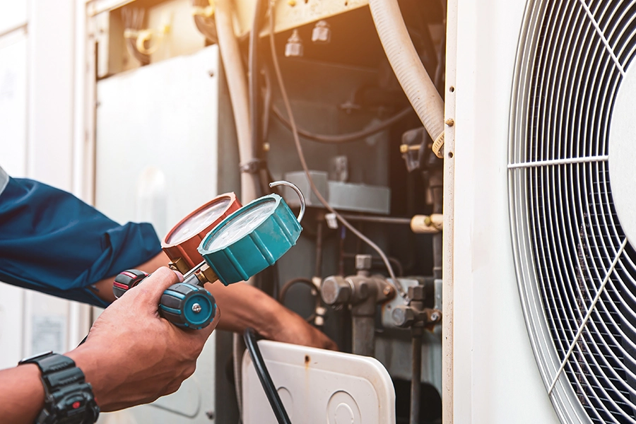 Technician checking the refrigerant levels while conducting air conditioning maintenance on a unit in O’Fallon, IL.