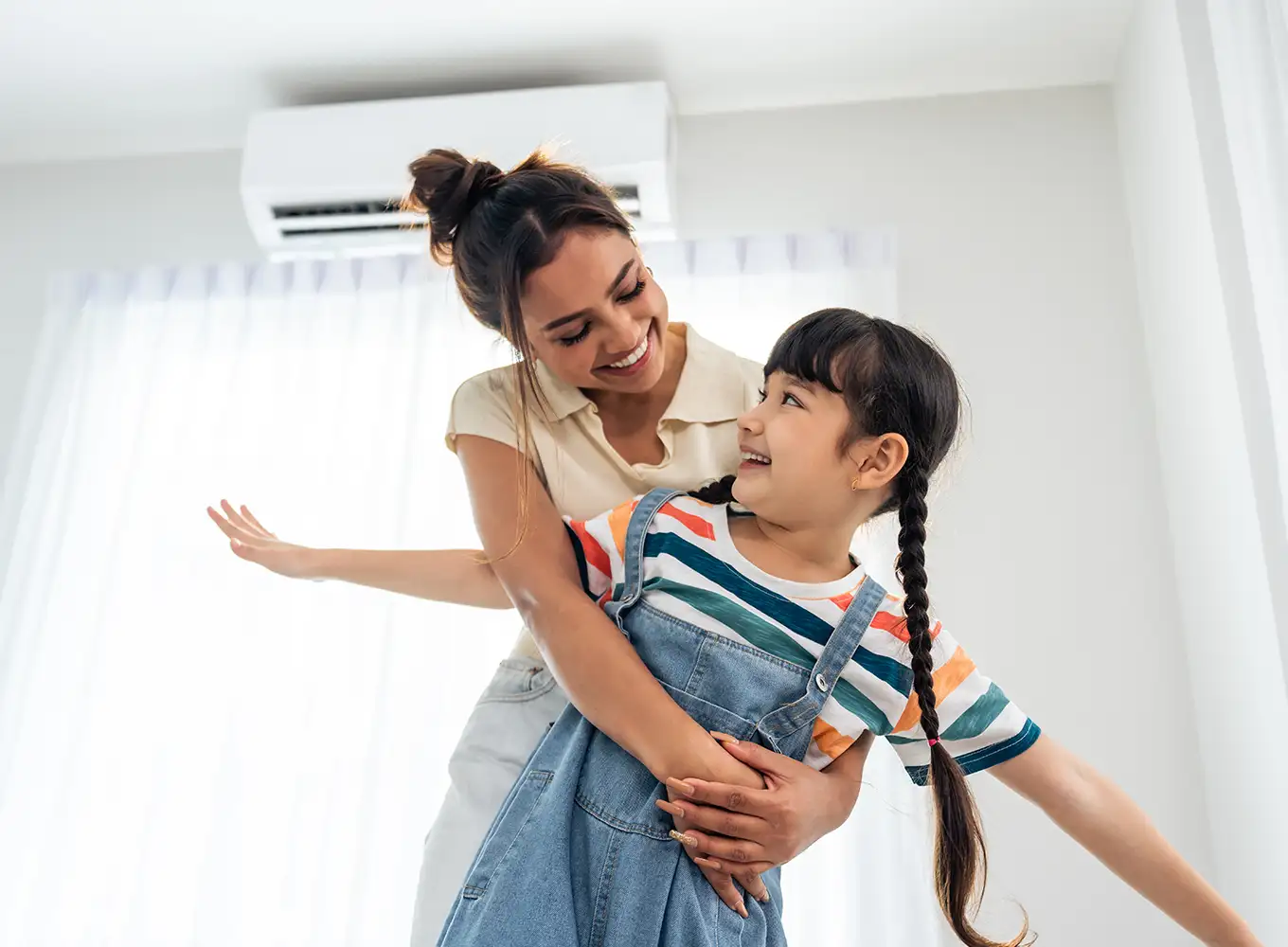 mother embracing her daughter in front of a ductless air conditioning system collinsville il