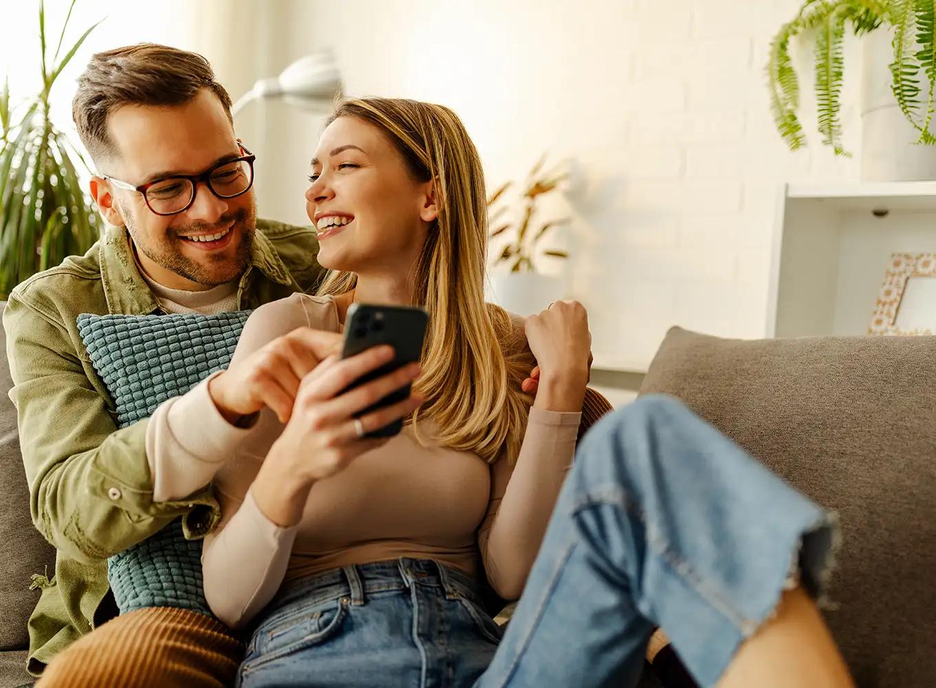 young married couple sitting on a couch in their comfortable home