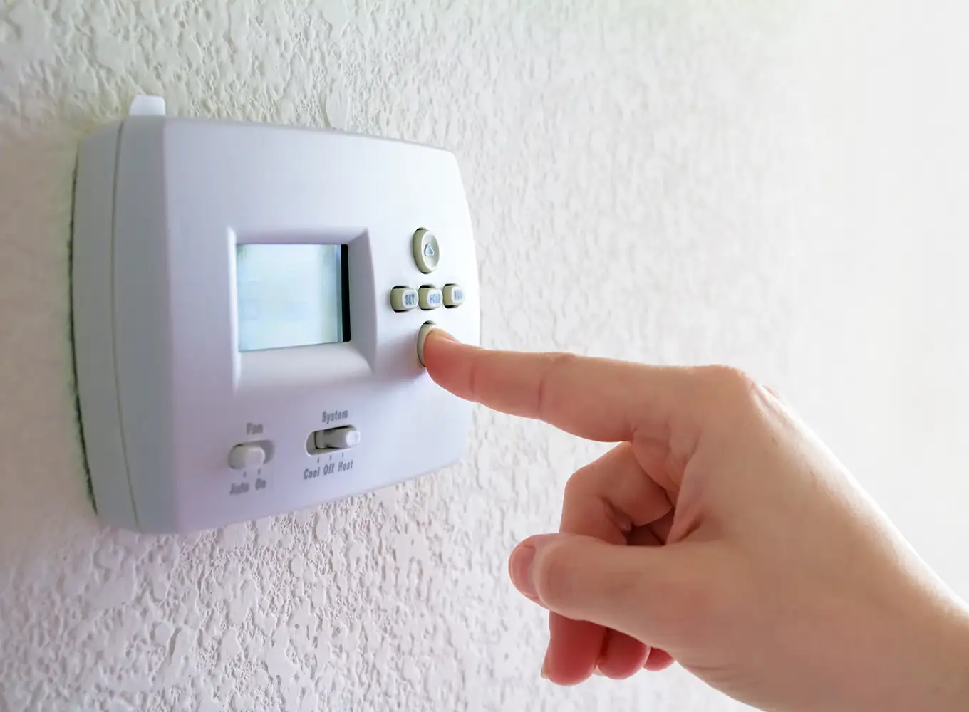 person changing the thermostat settings in their home collinsville il