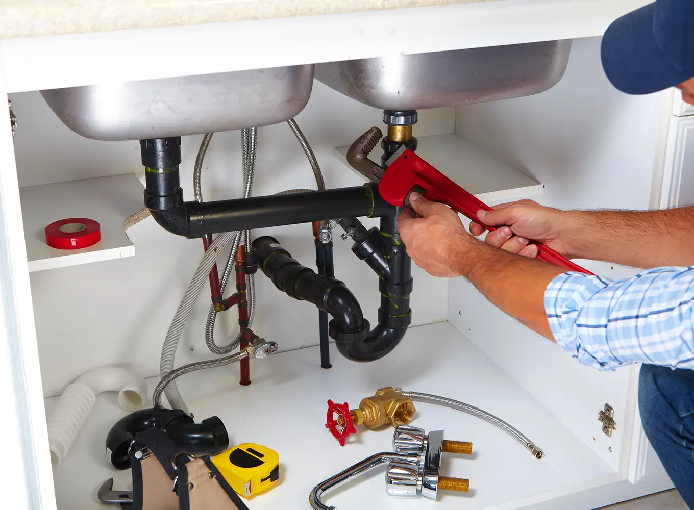 kitchen plumber repairing plumbing system underneath kitchen sink Collinsville illinois