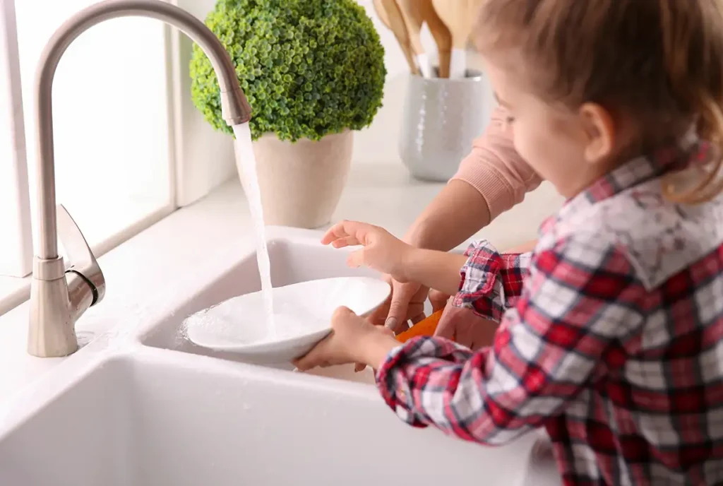 mother and daughter washing dishes in a kitchen sink