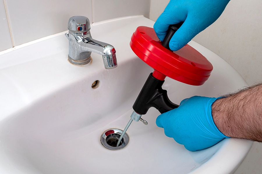 Plumber using advanced drain snake tool to clear clog out of drain in a bathroom in Granite City, IL.