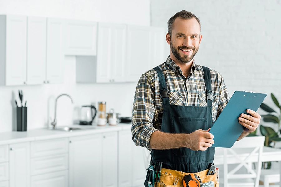 A male plumber holds a clipboard full of tips to help Collinsville, IL homeowners avoid winter freezing in their pipes.