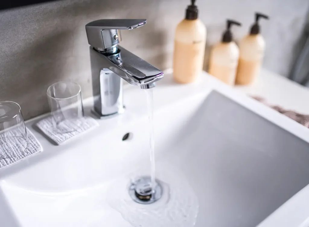 a bathroom faucet running with the water flowing into the drain