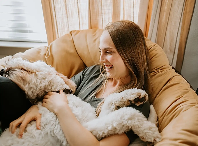 young woman with her dog sitting comfortably in a chair