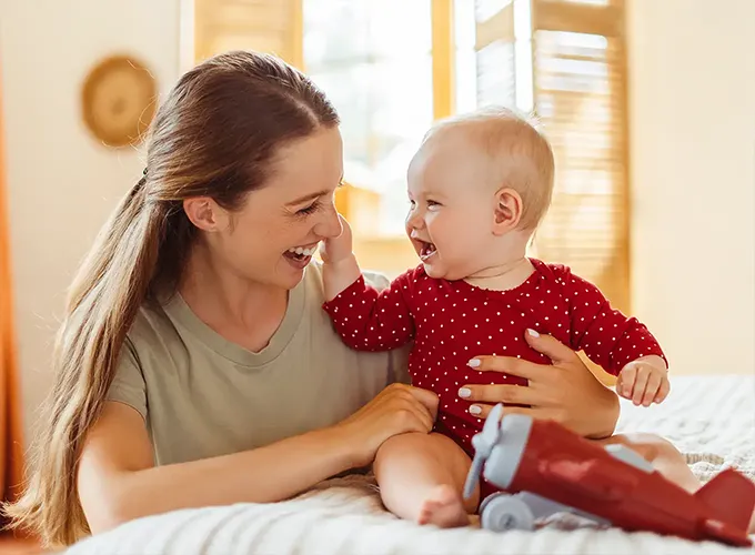mother and baby daughter smiling at each other in the comfort of their home