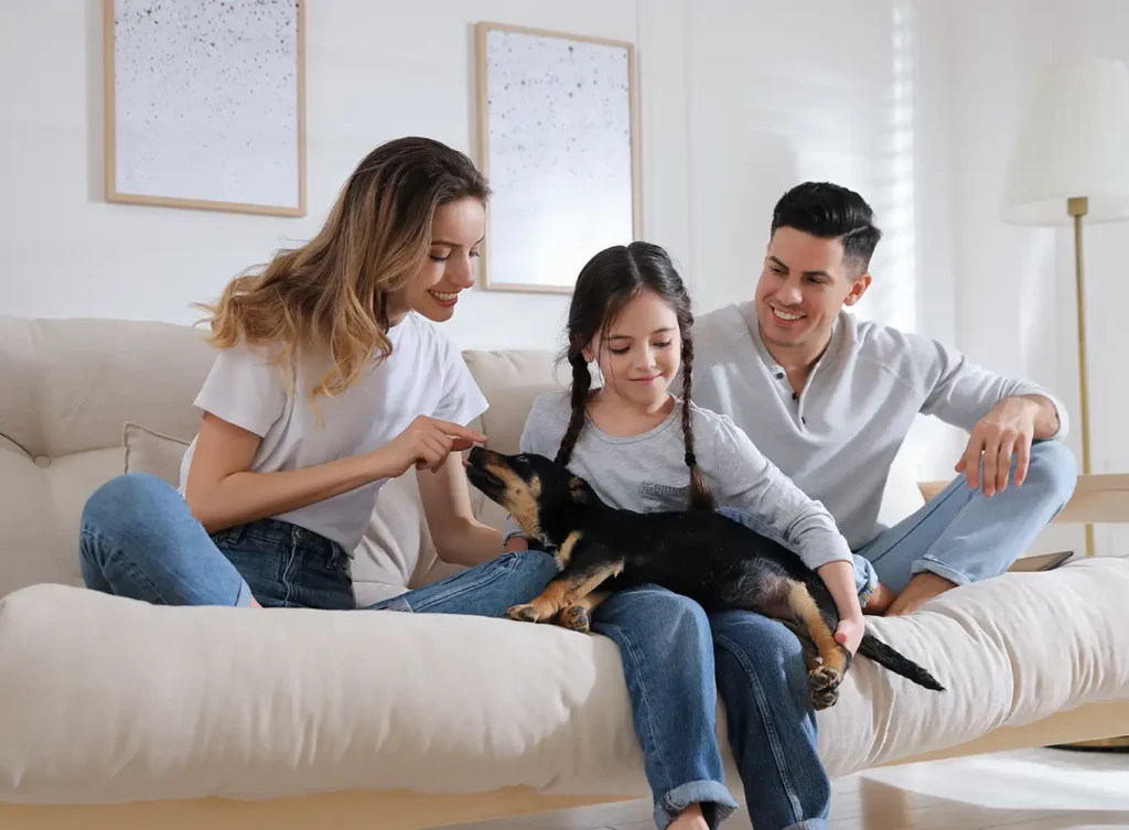 Family with dog sitting in house with comfort provided by Polar Plumbing Heating & Air Conditioning