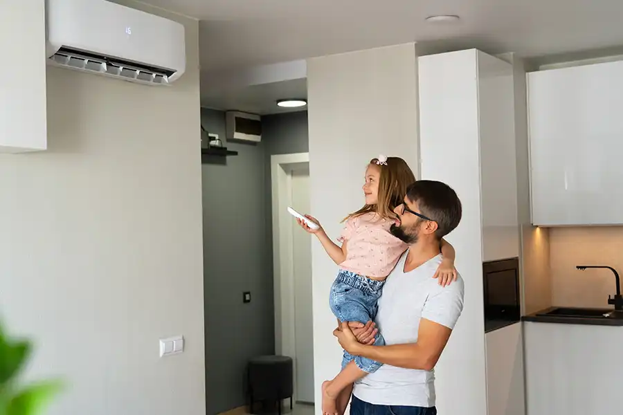 Polar—A father holding his daughter and letting her turn on the air conditioning unit with a remote inside their Collinsville, IL home.
