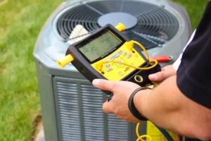 Polar – HVAC technician using a digital manifold gauge to check on a central air conditioning unit outdoors in Belleville, IL in order to determine if a homeowner needs to consider an ac repair or replacement.