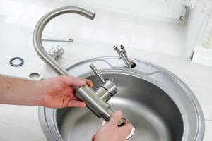 POLAR – A close-up of a plumber's hands holding a new faucet for installation into the kitchen sink in a home in Belleville, IL.