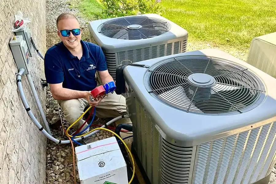 Jarod, owner of Polar, examines refrigerant levels of an AC unit outside a home in Troy, IL.