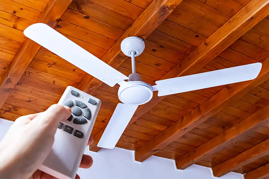 POLAR - Homeowner in Collinsville, IL, holding the remote to a ceiling fan, getting ready to turn it on.